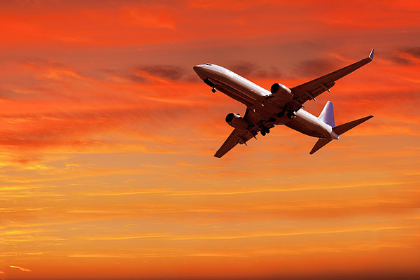 Airplane Flying In Red Sky At Sunset Greeting Card by Buena Vista Images