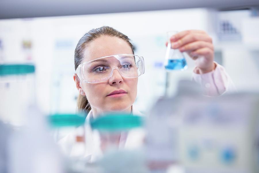 Lab Assistant Holding Chemical Flask #1 by Science Photo Library