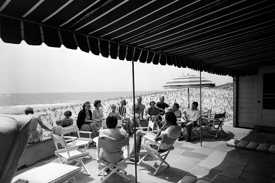 Gathering Under Beach Canopy Photograph - A Group Of People On A Terrace Overlooking by Tom Leonard