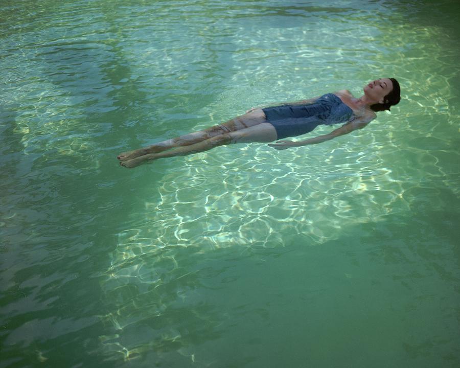 Woman Relaxing in Pool Photograph - A Model Floating In A Swimming Pool by John Rawlings