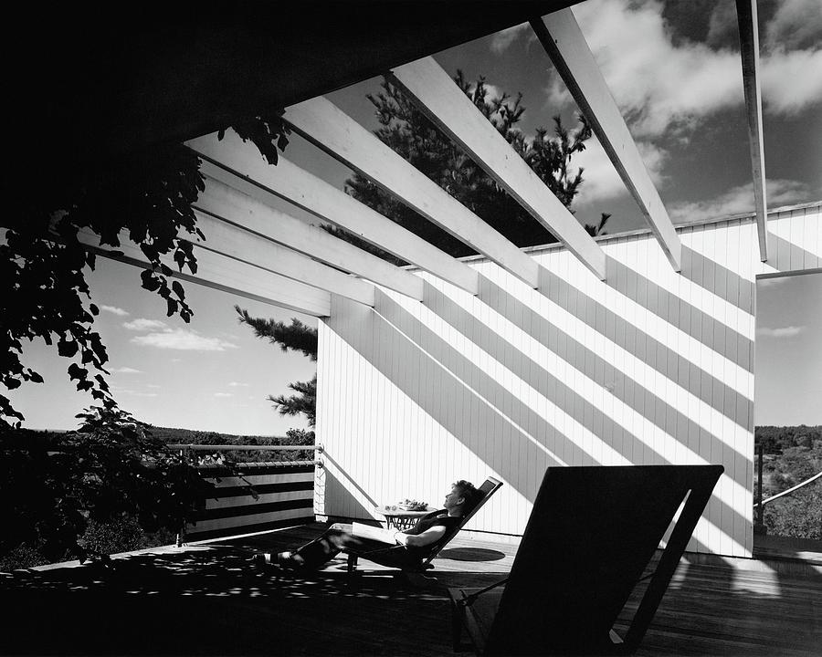 Relaxing in Modern Architecture Photograph - A Woman Sitting On A Reclining Chair On A Rooftop by Robert M. Damora