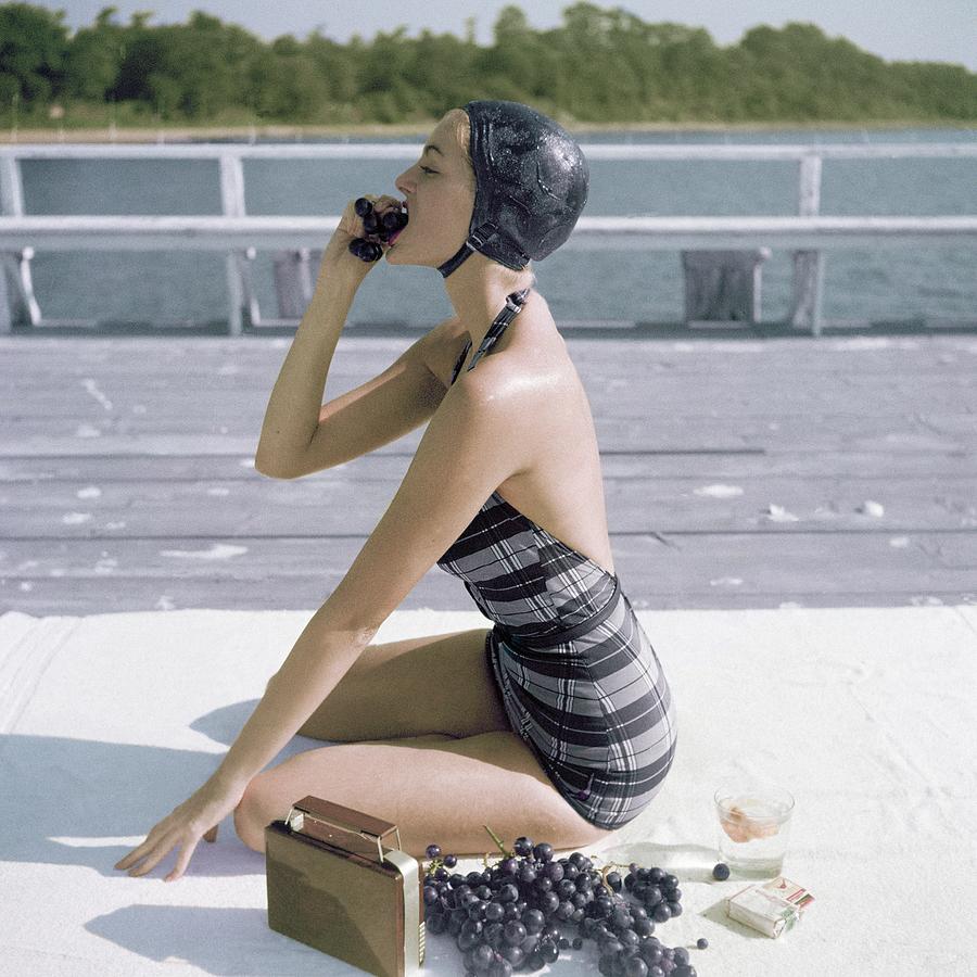 Vintage Woman Sunbathing By the Pier Photograph - A Young Woman Wearing A Swimsuit Eating Grapes by John Rawlings