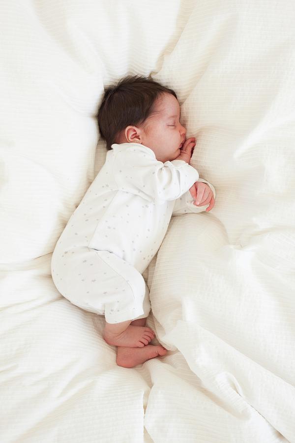 Baby Asleep On Bed by Ian Hooton / Science Photo Library
