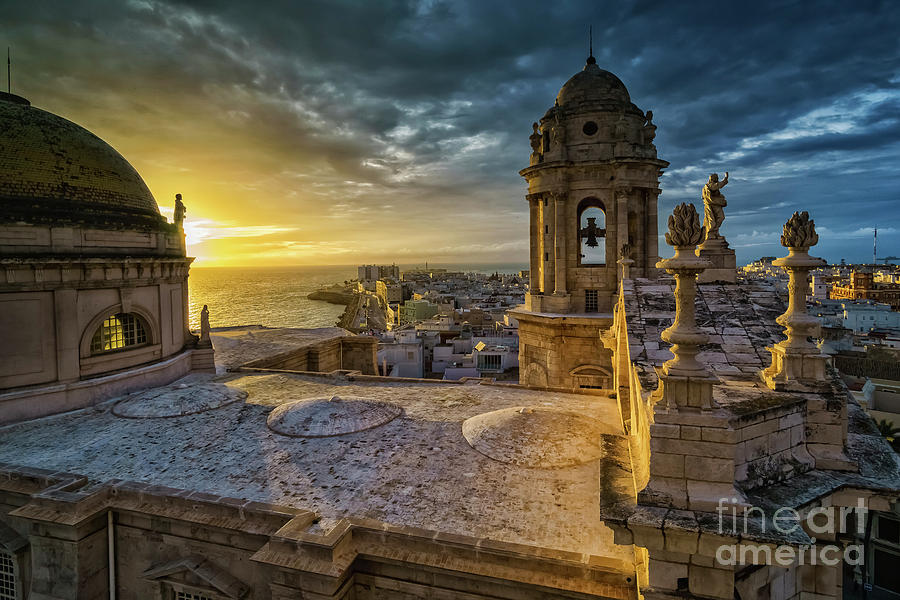 Colour photograph of Cadiz Cathedral at sunset from the Levante Tower, with golden stone dome and towers above the Atlantic and city rooftops