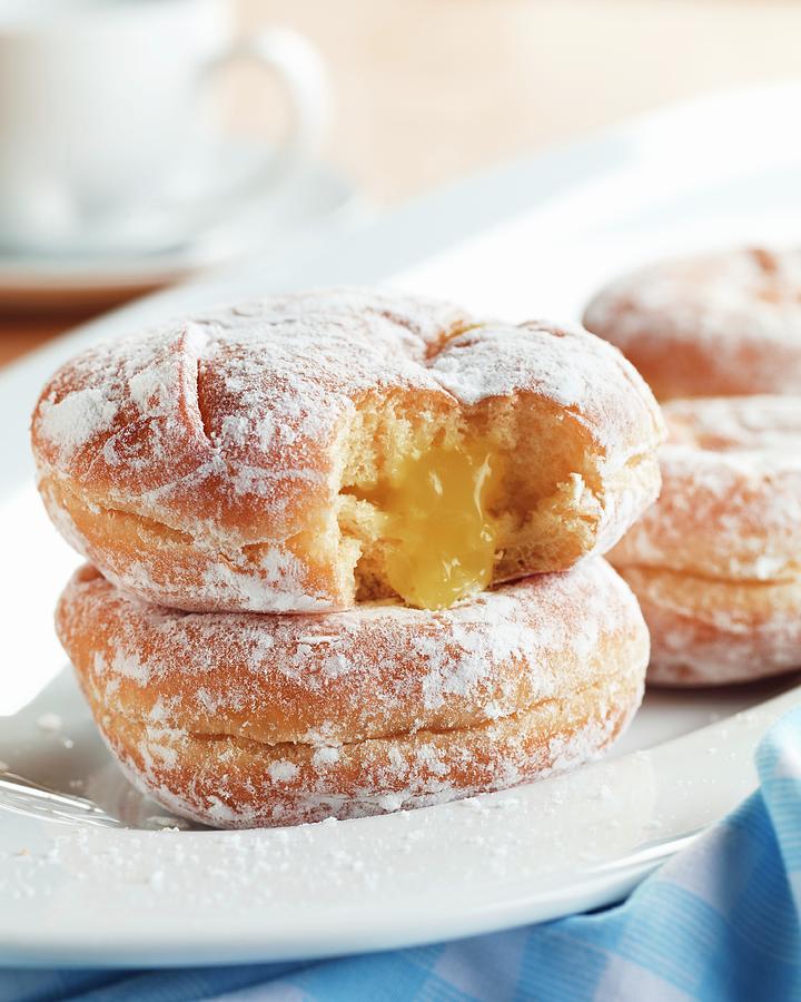 Lemon Jelly Filled Powdered Doughnuts On A White Dish; One Bitten With Jelly Oozing Out Photograph by Harrison, Michael S.