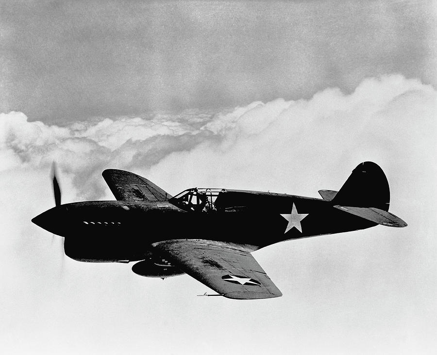 A vintage wartime fighter plane with a star insignia, flying through a cloudy sky, showcasing early aviation military history.