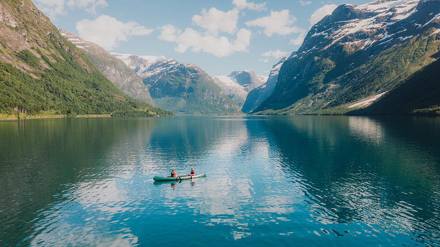 Aerial view of woman and man contemplating summer in Norway canoeing in the lake Lovatnet #1 Photograph by Anastasiia Shavshyna