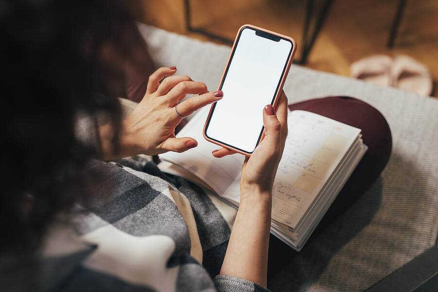 Anonymous Woman Using her Mobile Phone at Home (Blank Screen, Copy Space) #1 Photograph by FreshSplash