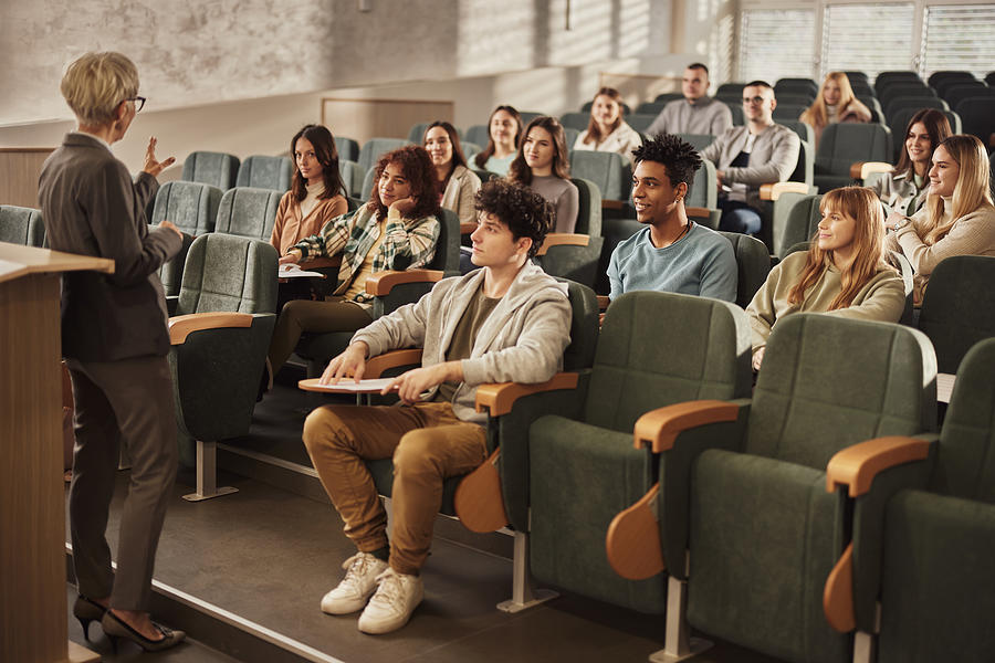 College students listening to their senior teacher on a class at lecture hall. #1 Photograph by Skynesher