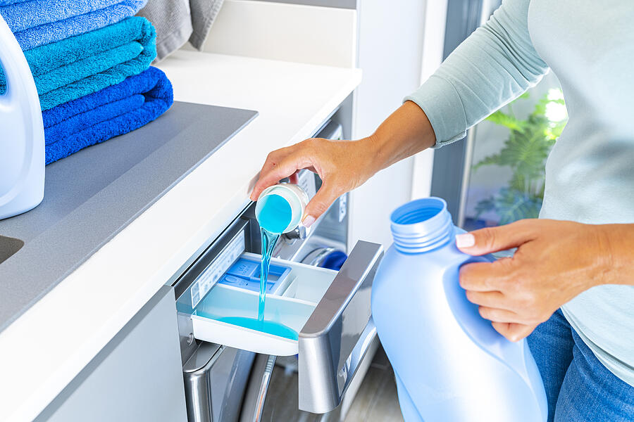Woman adding fabric softener or detergent to a washing machine #1 Photograph by Fcafotodigital
