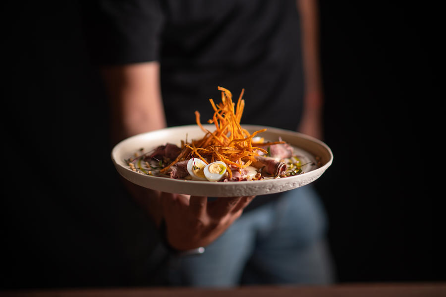 A male chef serving a fine dining dish in a restaurant Photograph by Ilkermetinkursova
