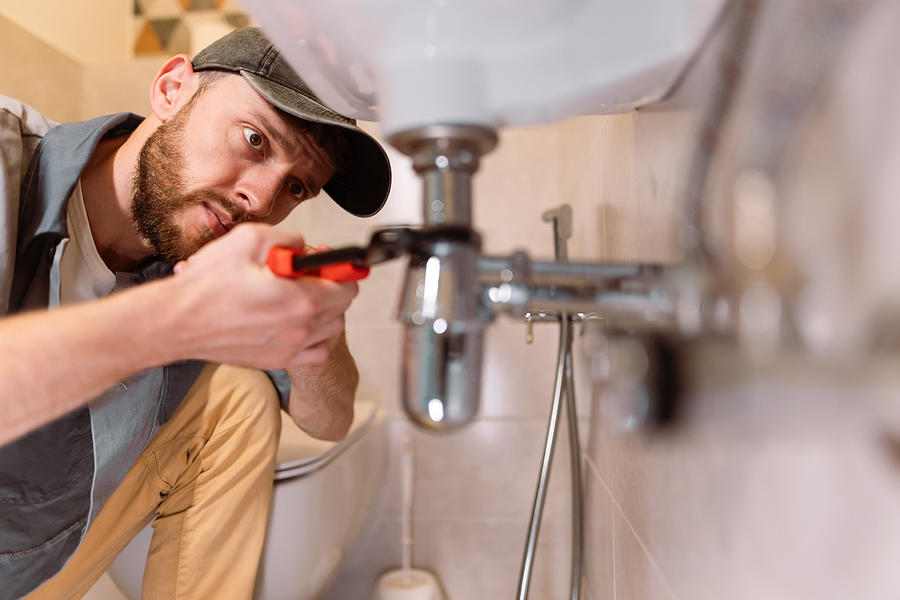 A Plumber Carefully Fixes A Leak In A Sink Using A Wrench Nazar Rybak