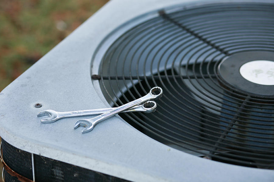 An air conditioner being fixed Photograph by JaniceRichard
