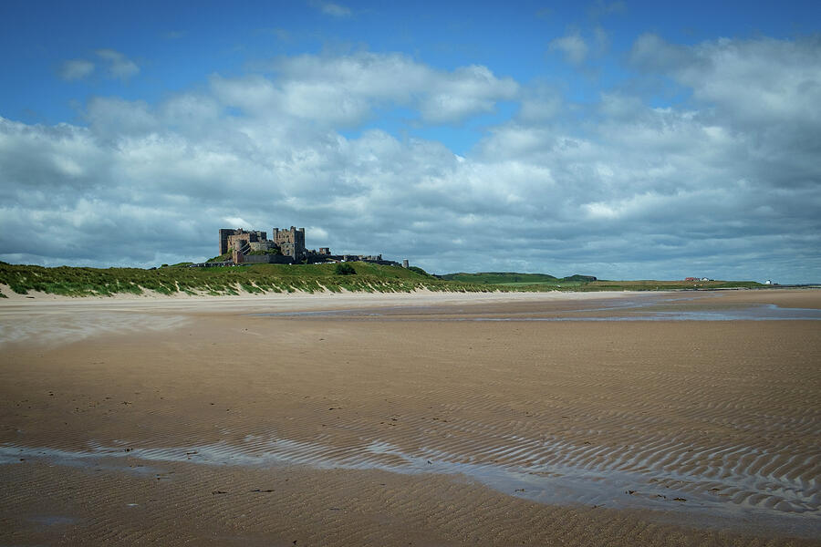 Castle by the Sandy Shore Photograph - Bamburgh Castle on the horizon above Bamburgh beach by Seeables Visual Arts