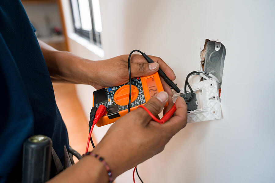 Electrician Fixing An Electrical Outlet And Measuring The Voltage Andresr
