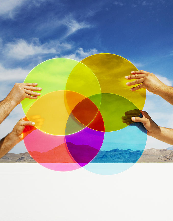 Hands holding multi-colored discs in landscape. Photograph by Andy Ryan