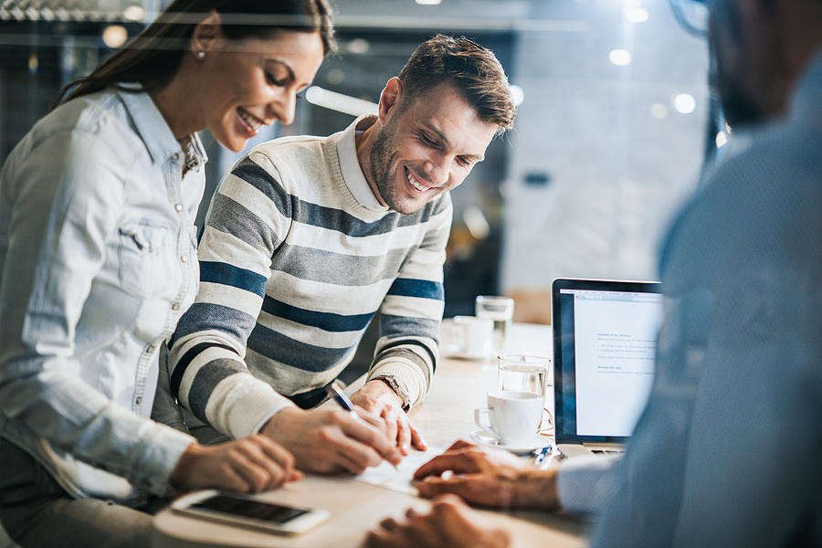 Happy couple signing a contract on a business meeting with their insurance agent. Photograph by Skynesher