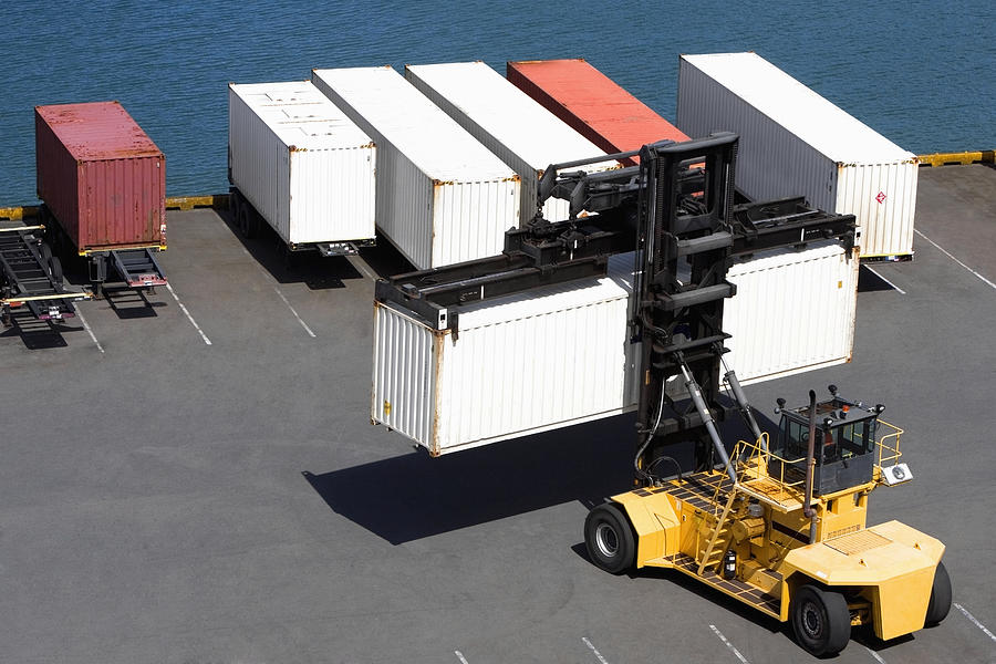 High Angle View Of A Forklift Picking Up A Cargo Container At A Commercial Dock Glowimages