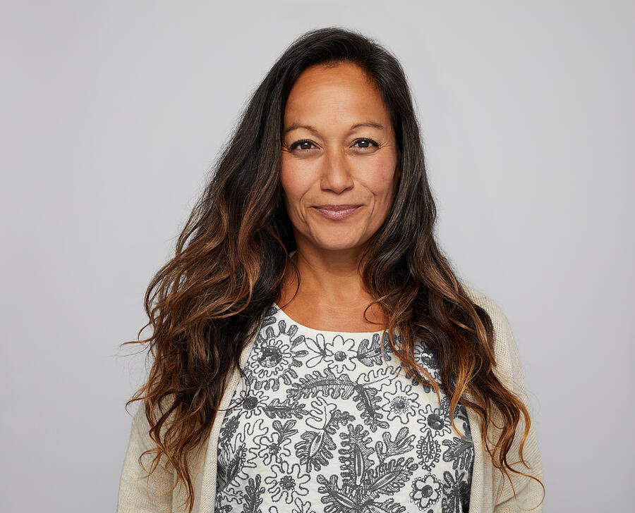 Mature woman smiling confidently in front of a gray background Photograph by Goodboy Picture Company
