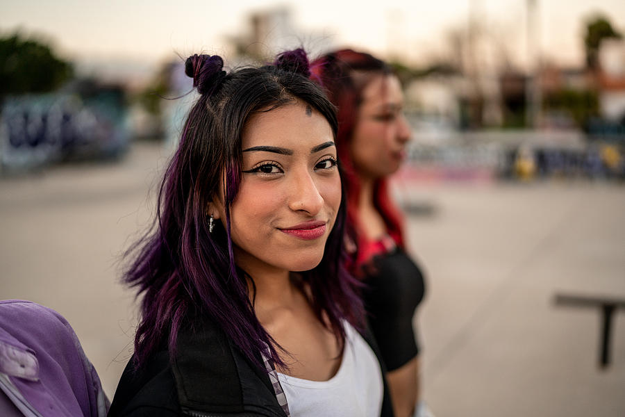 Portrait of young woman walking with her friends at skateboard park Photograph by FG Trade Latin