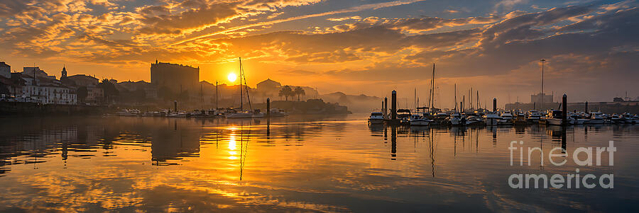 Boats moored in the marina at the Port of Ferrol silhouetted against a golden sunrise and reflected in still water