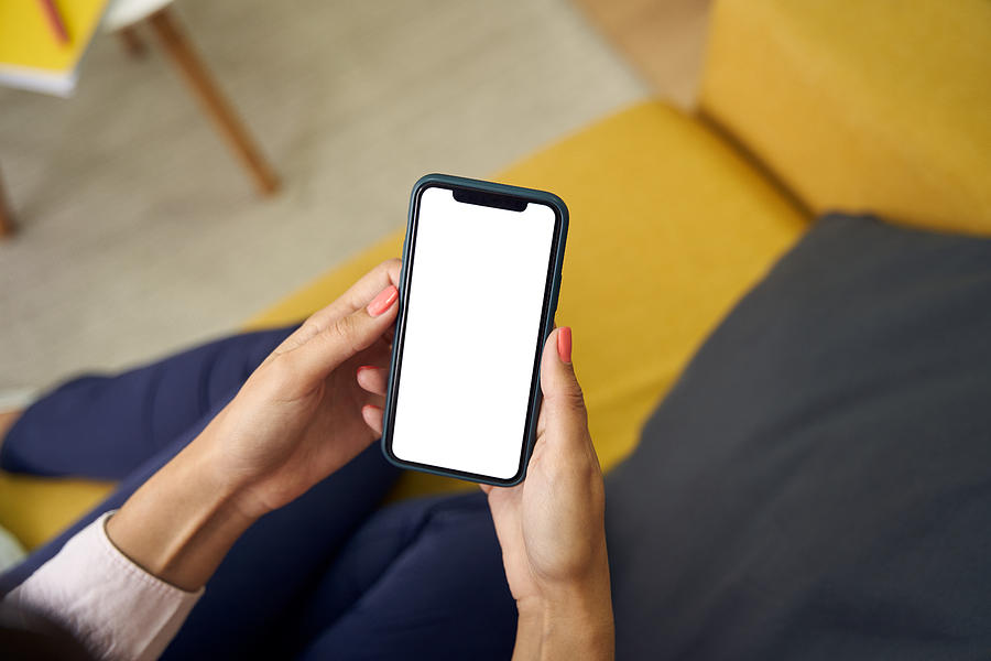 Top view of an unrecognizable womans hands using her mobile phone with a blank screen. Photograph by Alvaro Medina Jurado