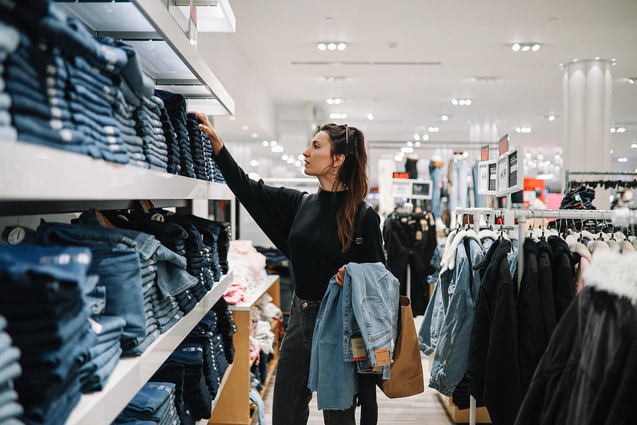 Woman Shopping Denim Jeans In A Clothing Store Photograph by Lechatnoir