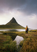 Young hiker with a backpack looks at the Kirkjufell mountain in Iceland #1 Photograph by Miroslav Liska